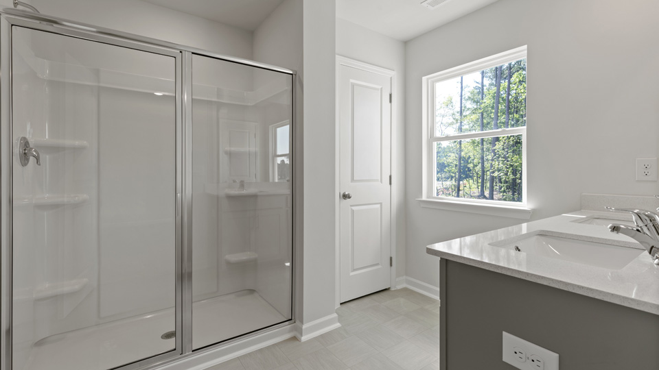 primary bathroom with double vanity and window and walk-in shower