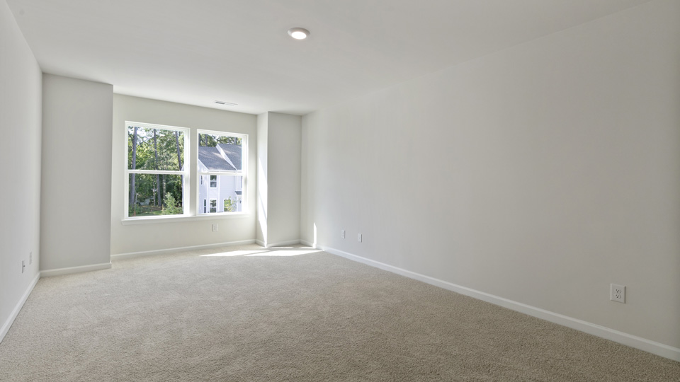 primary bedroom with large windows and attached bathroom, carpet