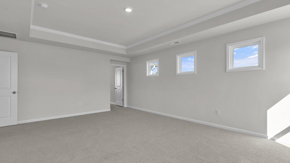 primary bedroom with two windows and carpeting, attached bath