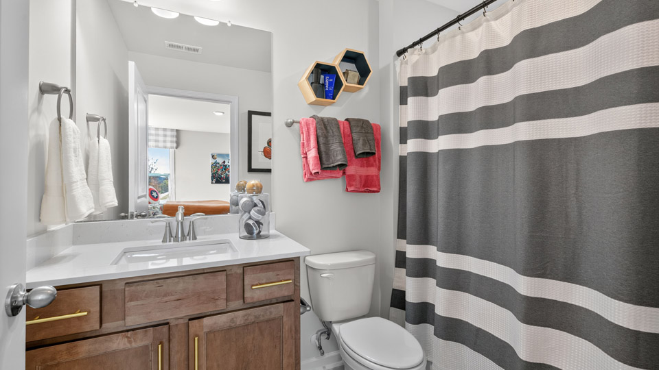 bathroom with brown cabinets quartz countertops and tub shower combo