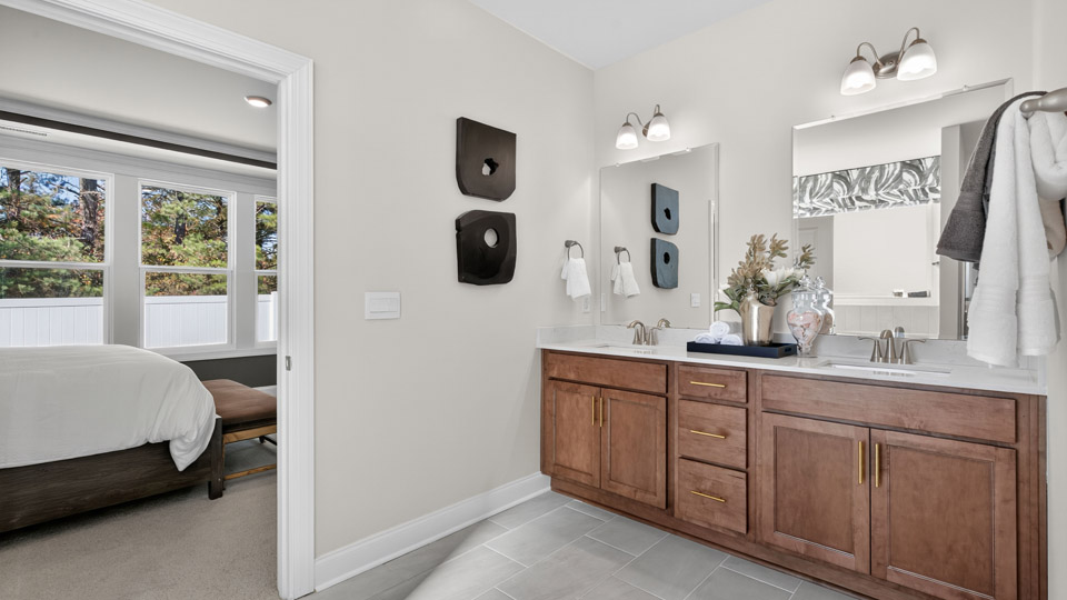 bathroom with dual vanity quartz countertops and brown cabinets