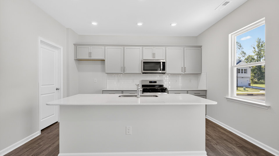 kitchen with quartz counters, kitchen island, pantry, stainless steel appliances