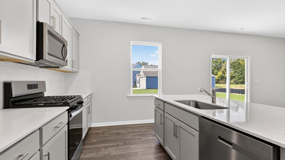 kitchen with quartz counters, kitchen island, pantry, stainless steel appliances