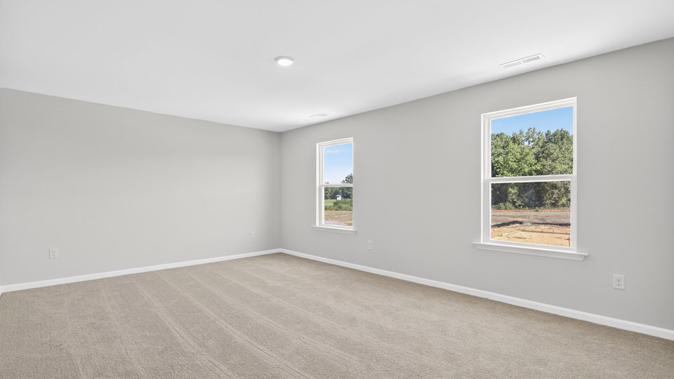 primary bedroom with two windows and carpeting, attached bath