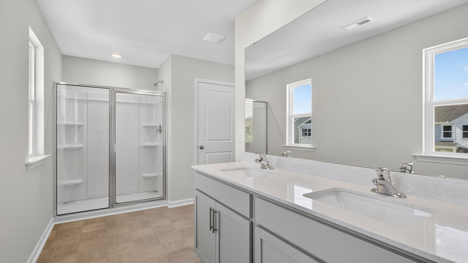 primary bathroom with walk in shower and dual vanity sinks