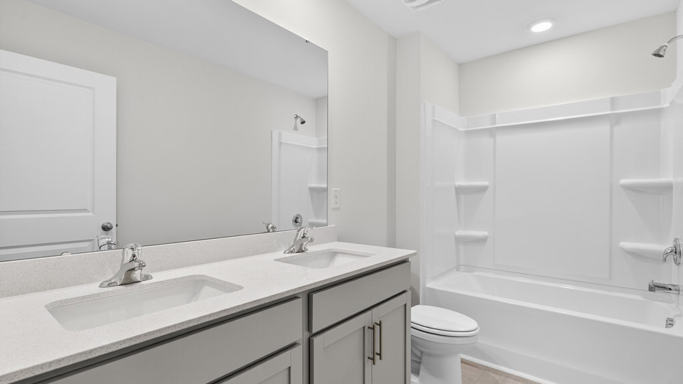 secondary bathroom with shower tub combo and dual vanity sink