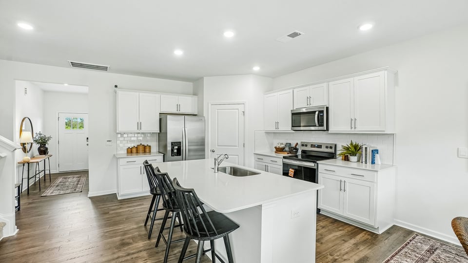 kitchen with quartz counters, kitchen island, pantry, stainless steel appliances