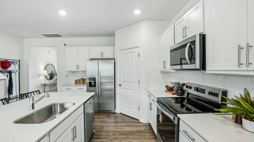 kitchen with quartz counters, kitchen island, pantry, stainless steel appliances