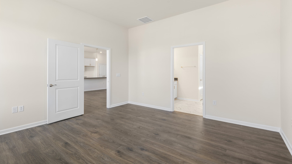 primary bedroom with two windows and revwood, attached bath