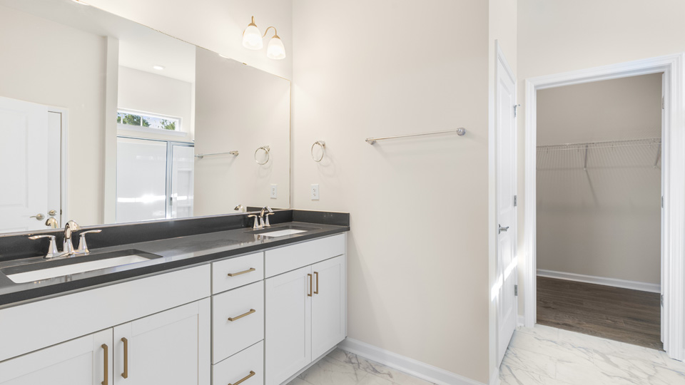 primary bathroom with walk in shower and dual vanity sinks
