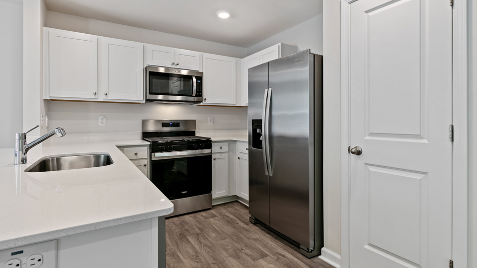 kitchen with quartz counters, kitchen island, pantry, stainless steel appliances