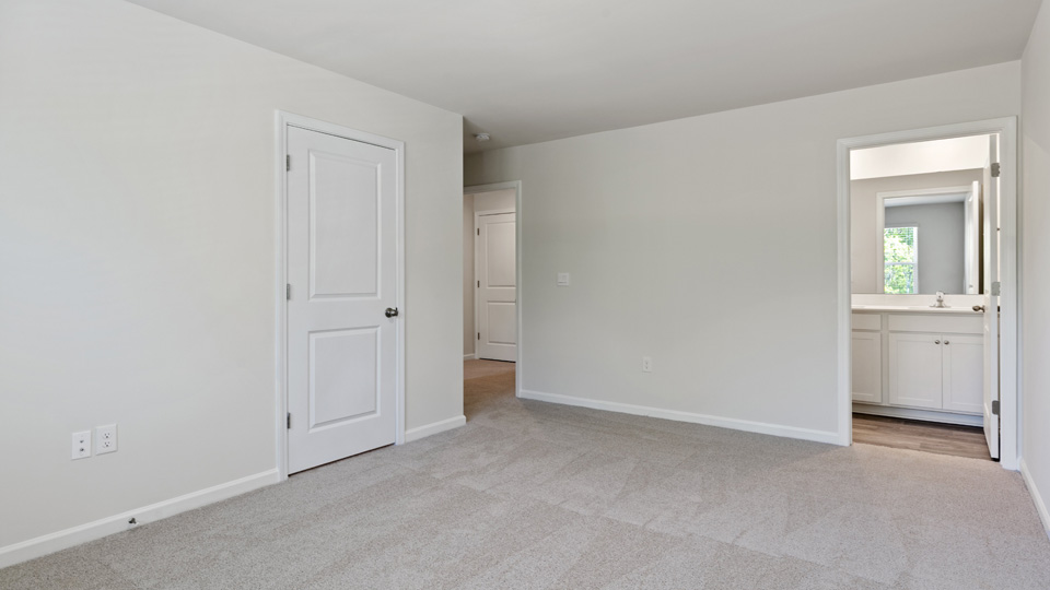 primary bedroom with two windows and carpeting, attached bath