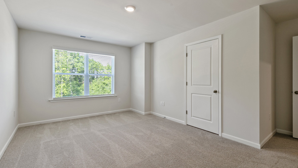 primary bedroom with two windows and carpeting, attached bath