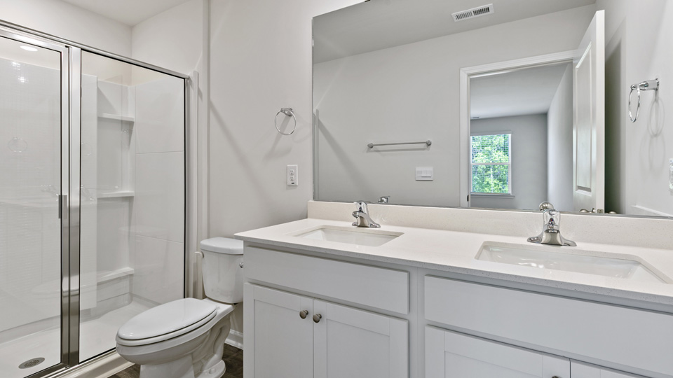 primary bathroom with walk in shower and dual vanity sinks