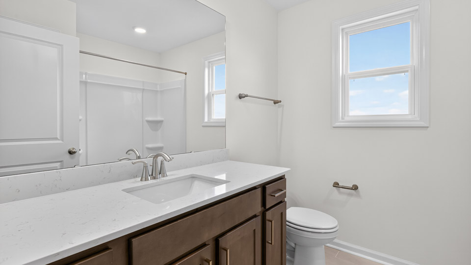 bathroom with brown cabinets quartz countertops