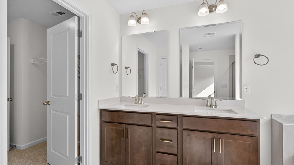 bathroom with dual vanity brown cabinets and quartz countertops