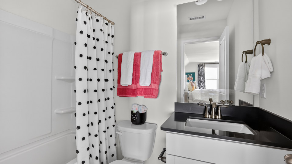 bathroom with tub shower combo and white cabinets