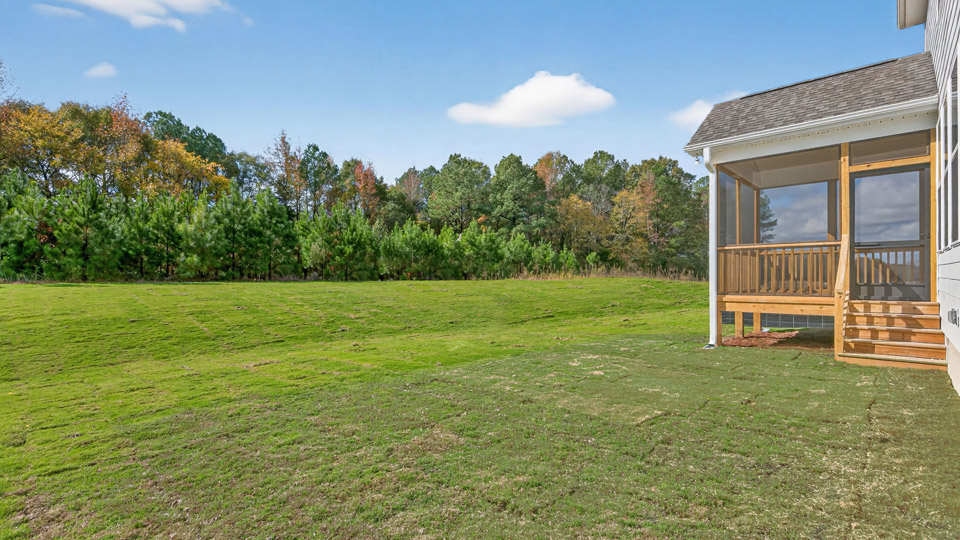 spacious treelined backyard with covered and screened in back deck