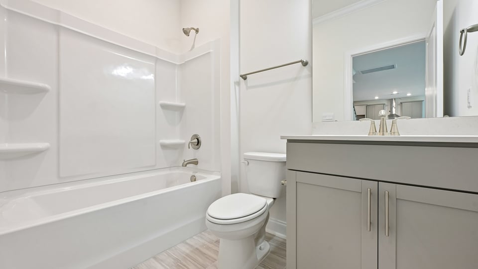 bathroom with gray cabinets tub shower combo and quartz countertops