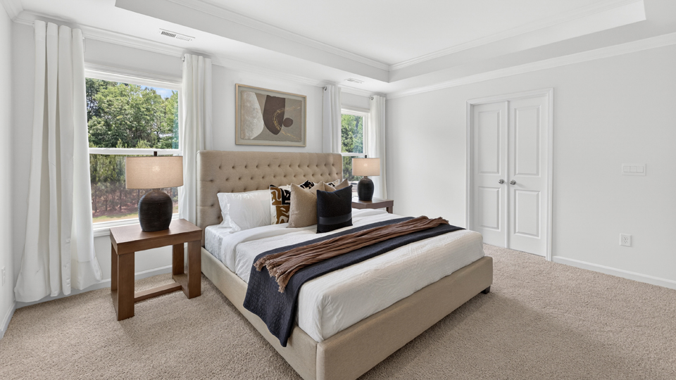 primary bedroom with two windows and carpeting, attached bath