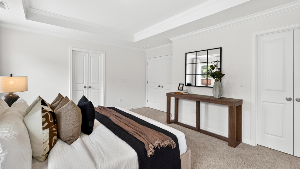 primary bedroom with two windows and carpeting, attached bath