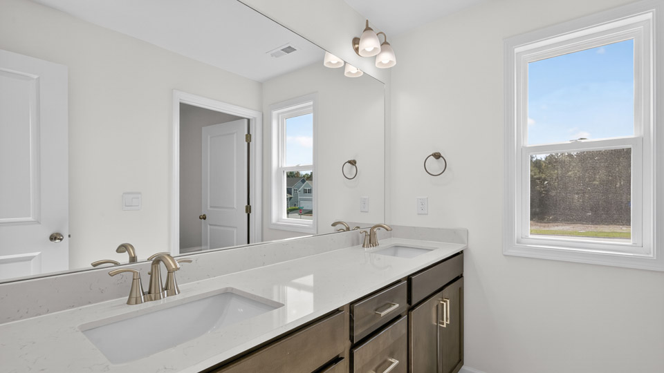 bathroom with dual vanity brown cabinets and quartz countertops