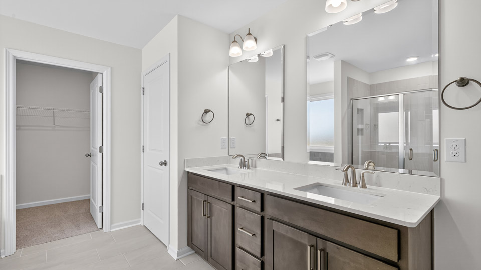 bathroom with dual vanity brown cabinets and quartz countertops