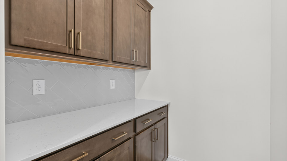 butlers pantry with quartz countertops and tile backsplash