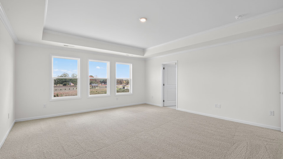 primary bedroom with two windows and carpeting, attached bath