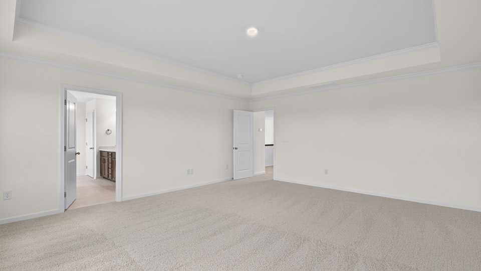 primary bedroom with two windows and carpeting, attached bath