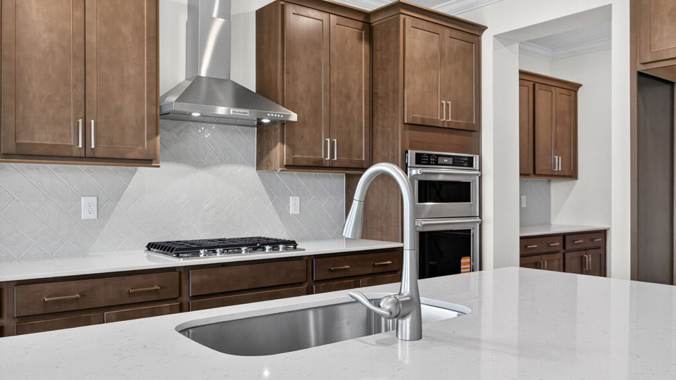 kitchen with quartz counters, kitchen island, pantry, stainless steel appliances