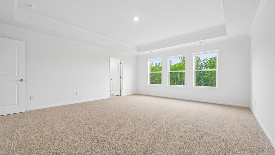 primary bedroom with two windows and carpeting, attached bath