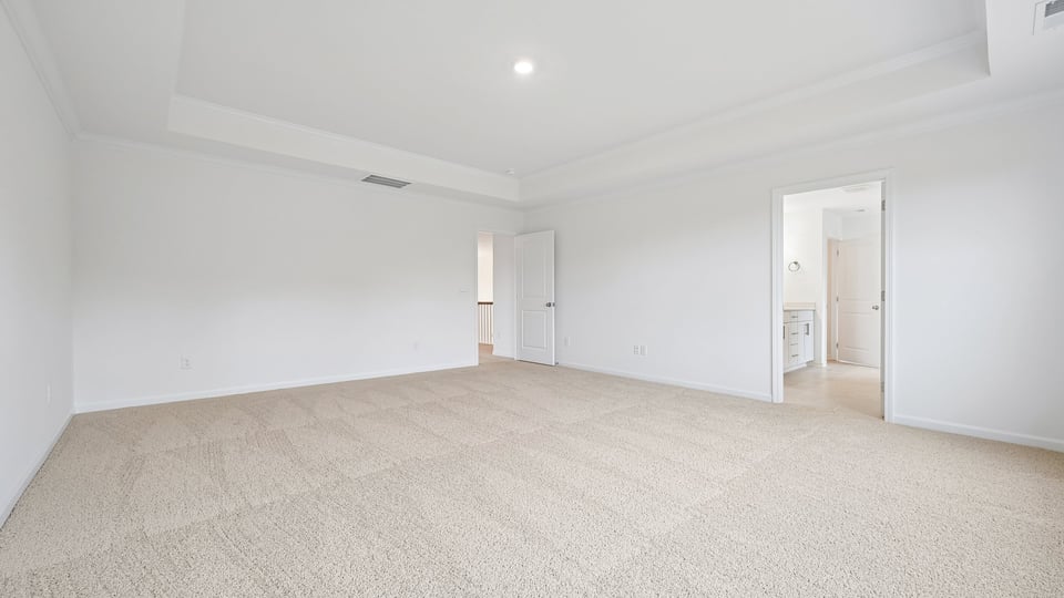 primary bedroom with two windows and carpeting, attached bath