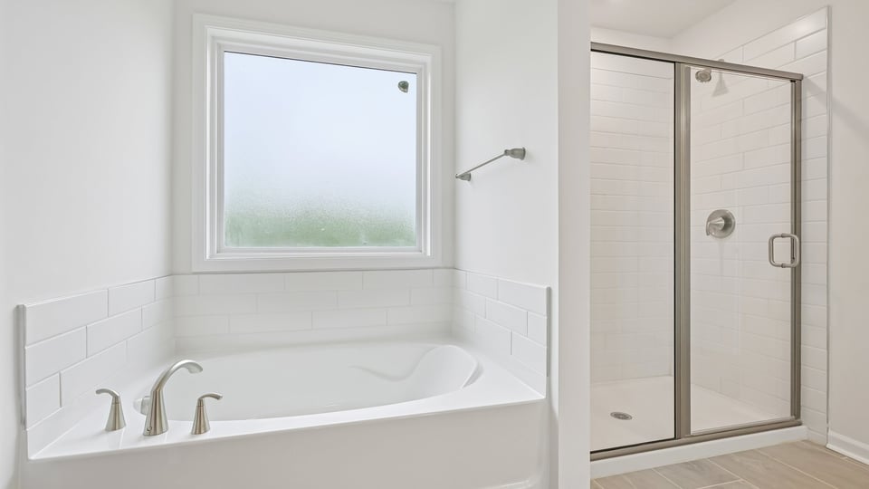 primary bathroom with walk in shower, bathtub, and dual vanity sinks