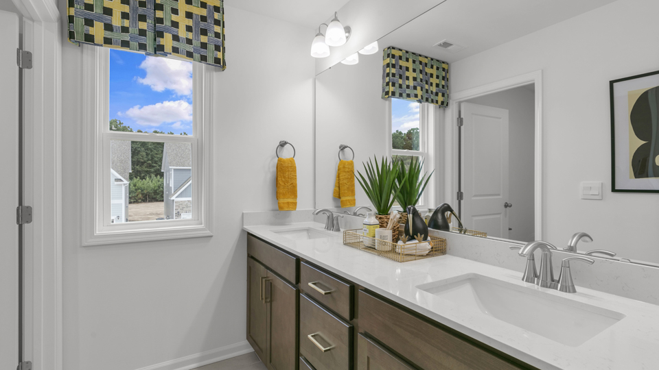 bathroom with brown cabinets dual vanity and quartz countertops