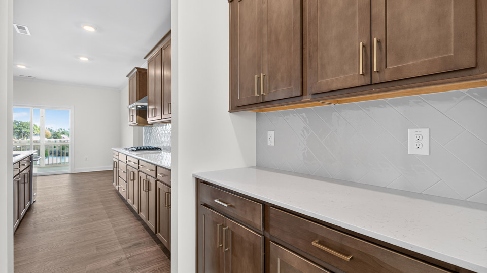 butlers pantry with brown cabinets quartz countertops and tile backsplash