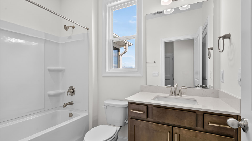 bathroom with brown cabinets quartz countertops and tub shower combo