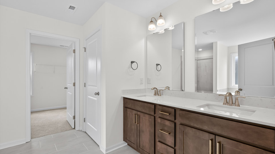 bathroom with dual vanity quartz countertops and brown cabinets