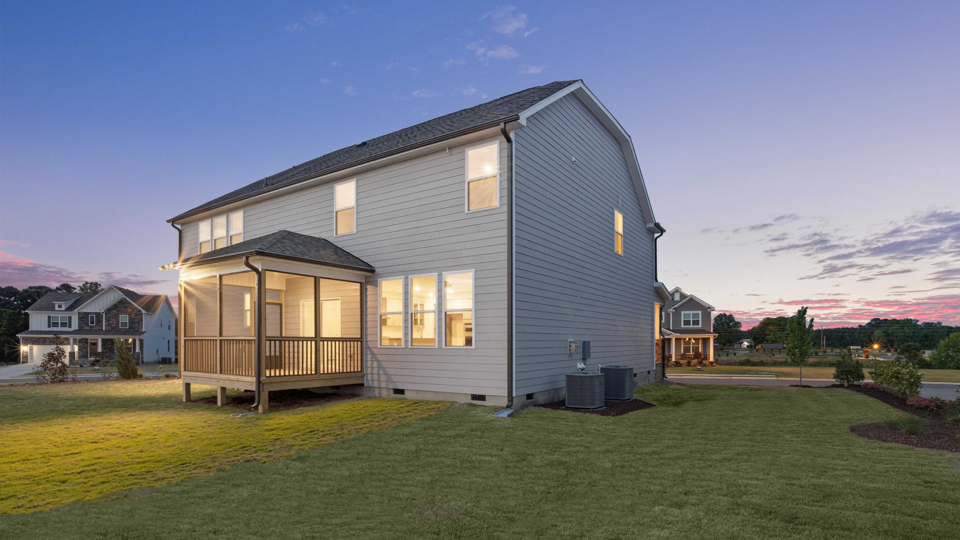 Norman D exterior back of home with covered and screened deck at twilight