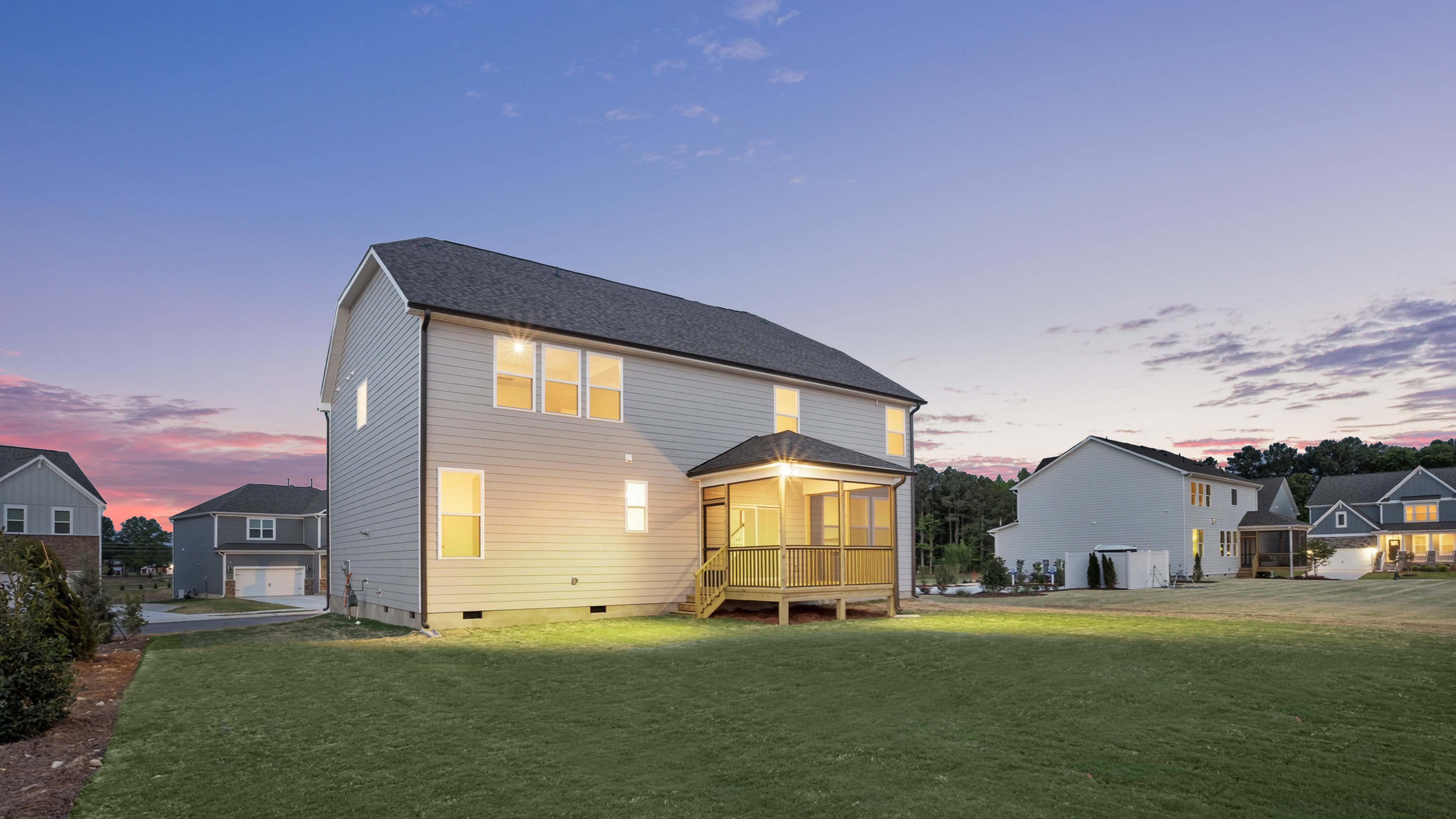 Norman D exterior back of home with covered and screened deck at twilight