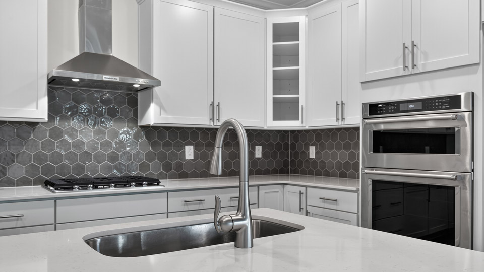 quartz countertops stainless steel appliances and ceramic tile backsplash