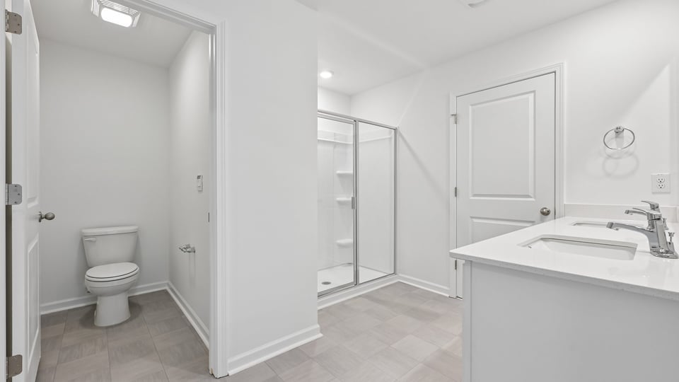 bathroom with water closet white cabinets and walkin shower