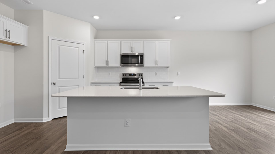 kitchen with quartz counters, kitchen island, pantry, stainless steel appliances