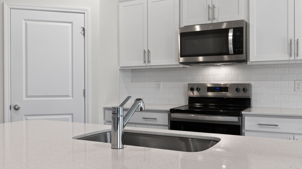 kitchen with quartz counters, kitchen island, pantry, stainless steel appliances