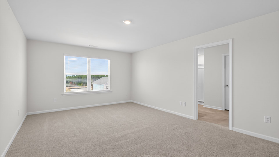primary bedroom with two windows and carpeting, attached bath