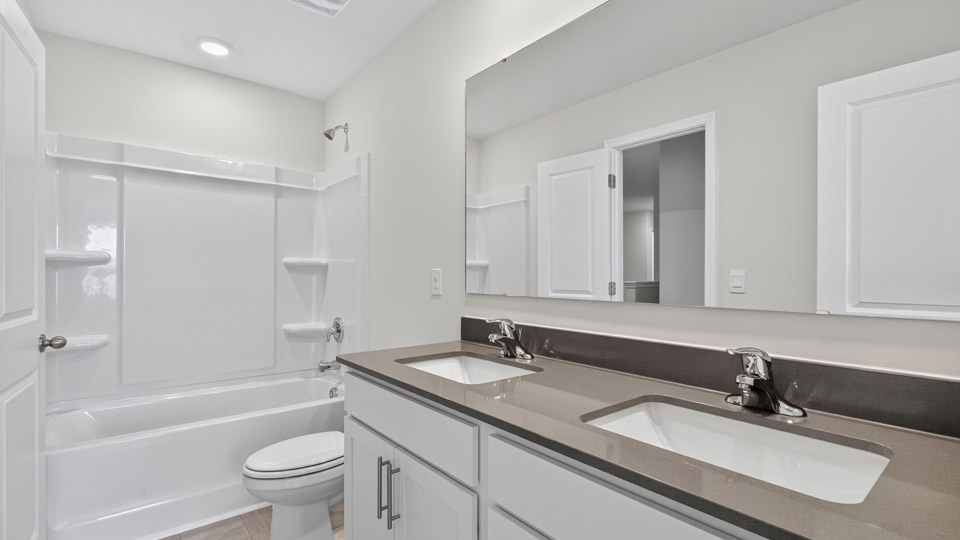 secondary bathroom with shower tub combo and dual vanity sink