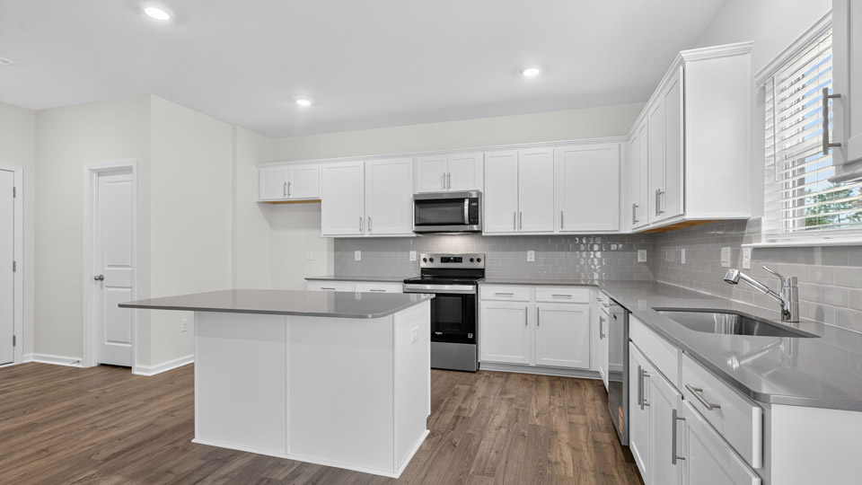 kitchen with quartz counters, kitchen island, pantry, stainless steel appliances