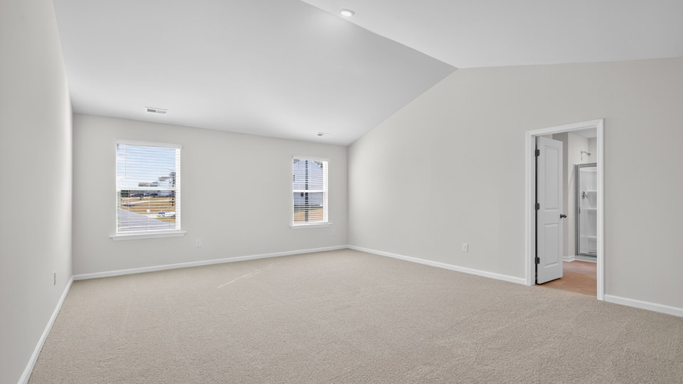 primary bedroom with two windows and carpeting, attached bath
