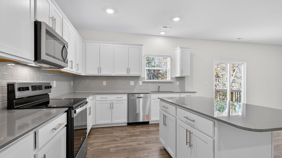 kitchen with quartz counters, kitchen island, pantry, stainless steel appliances