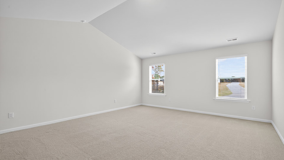 primary bedroom with two windows and carpeting, attached bath